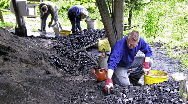 In mhevoller Handarbeit klaubt die K...hlenden Meiler die Holzkohlestckchen.  | Foto: Manfred Lange