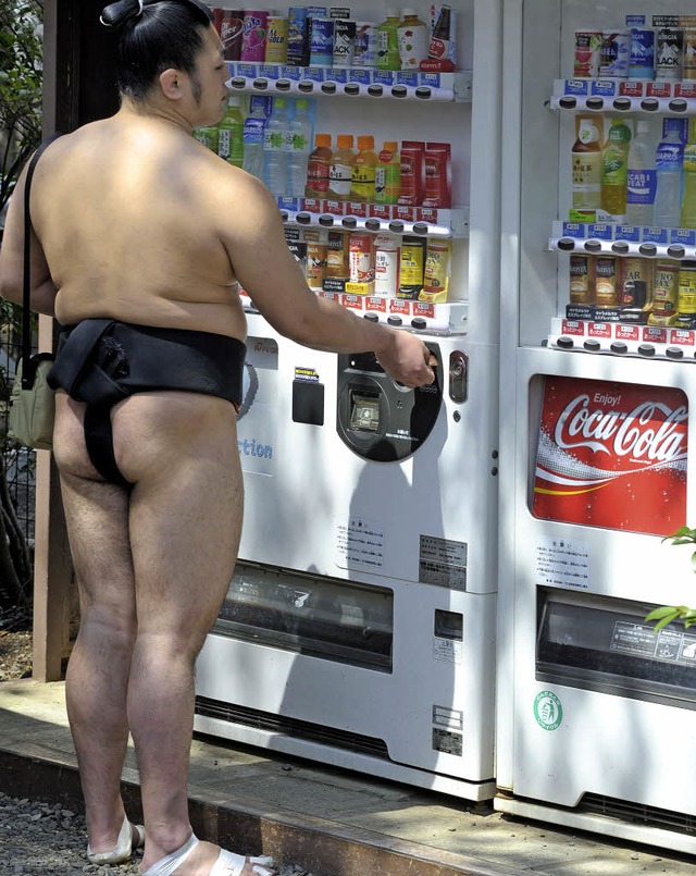 Ein durstiger Sumo-Ringer steht vor einem Getrnkeautomaten.  | Foto: AFP
