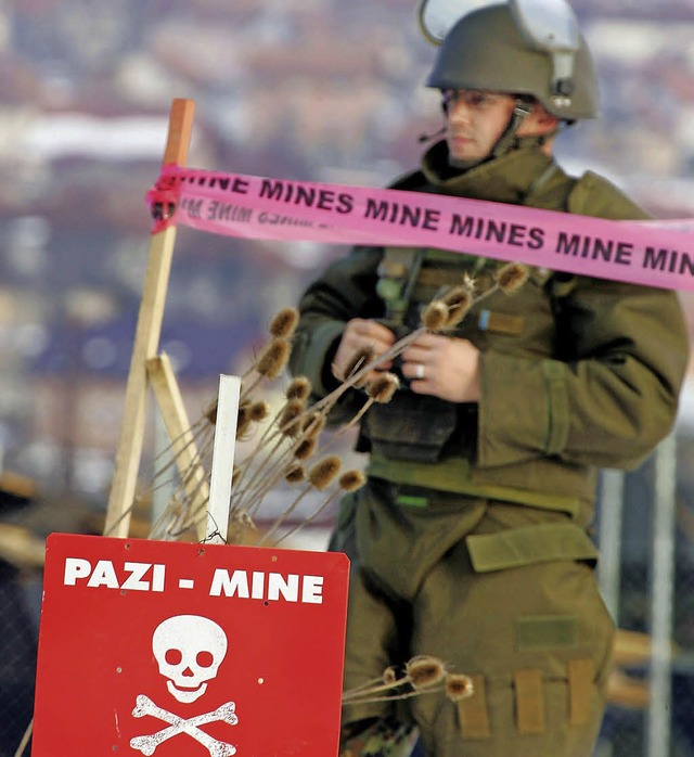 Ein Pionier der Bundeswehr steht in Bo...ter einem Schild, das vor Minen warnt.  | Foto: dpa