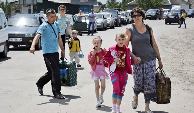 Eine Familie mit ihrem Gepck an der u...rteschlange am Grenzbergang zu sehen.  | Foto: dpa