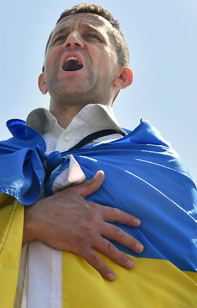 Ein Ukrainer auf dem Maidan in Kiew singt die Nationalhymne.   | Foto: AFP