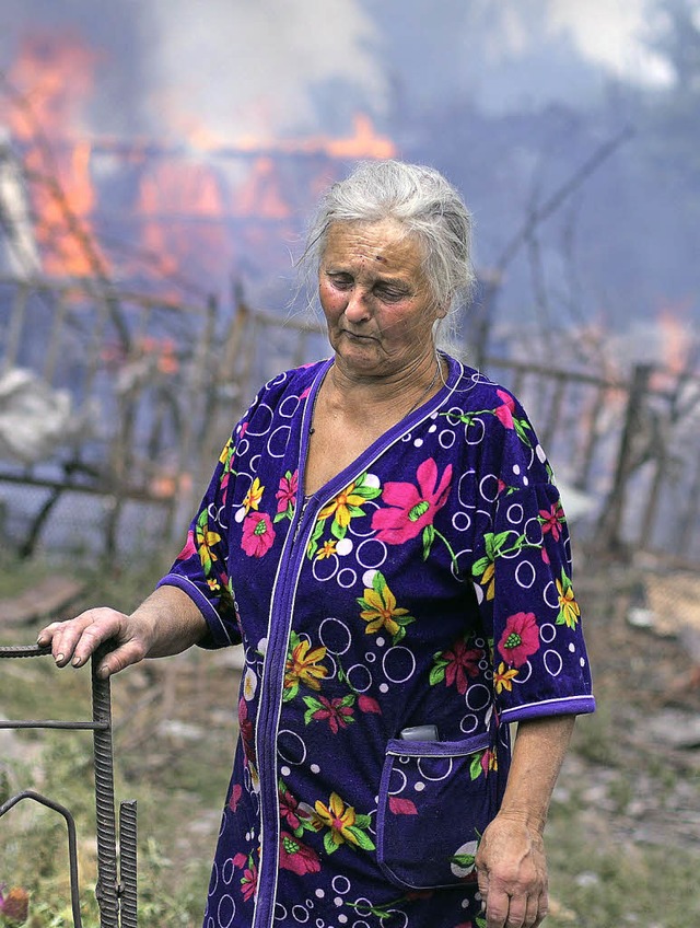 Eine Frau steht vor ihrem brennenden H...ainische Kampfbomber zerstrt haben.    | Foto: AFP