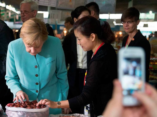 Was haben wir denn da? Merkel  auf einem Markt in Chengdu   | Foto: dpa