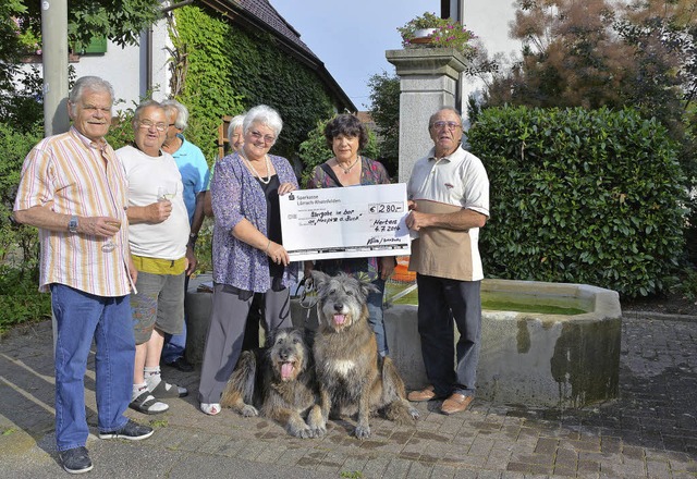 Einen Scheck in Hhe von 280 Euro ber...en mit einem Glas Hertener Wein  an.   | Foto: Heinz Vollmar