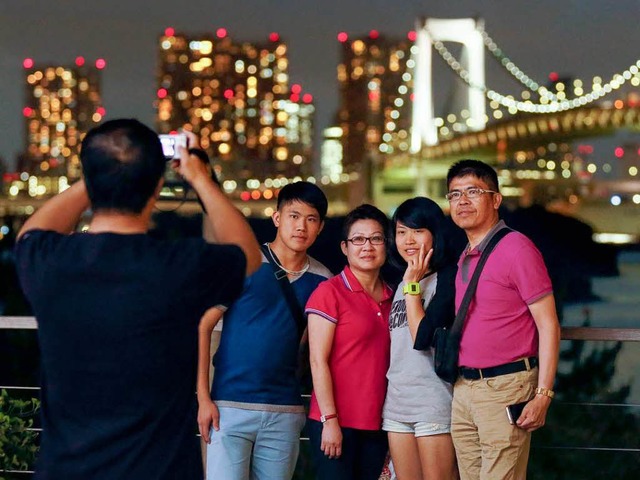 Einmal recht freundlich, bitte! Chines...posieren vor Tokios Skyline bei Nacht.  | Foto: DPA