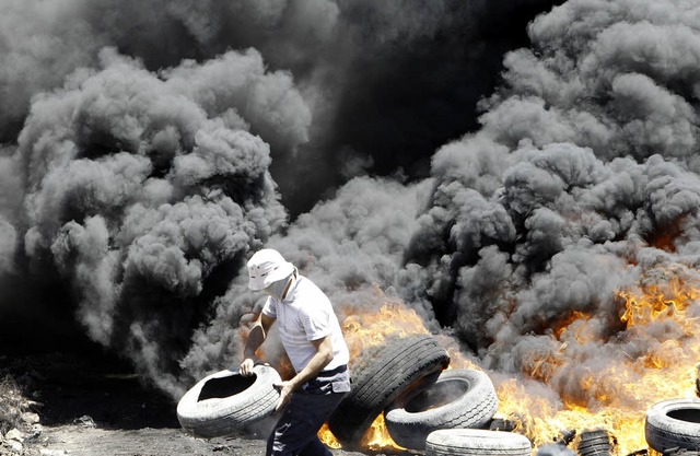 Ein Palstinenser zndet Reifen an wh...f Kfar Quaddum in der Nhe von Nablus.  | Foto: AFP