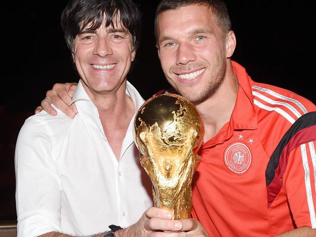Joachim Lw und Lukas Podolski halten das Ding fest.  | Foto: dpa