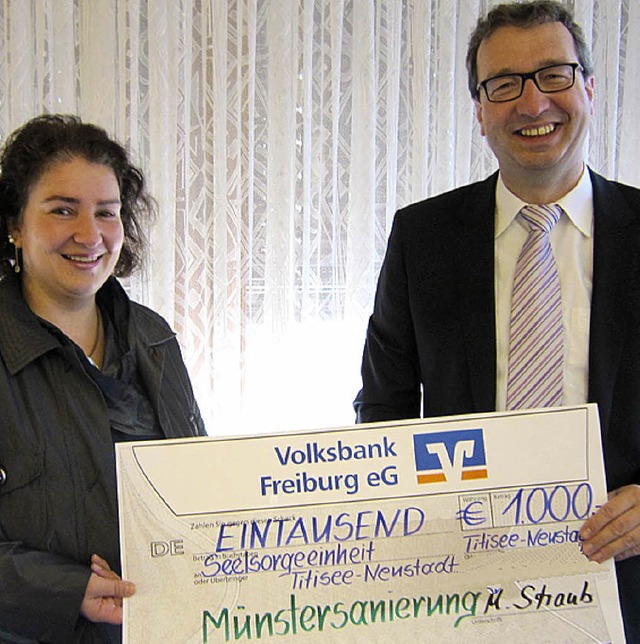 Pfarrer  Herrmann nimmt von Manuela Straub den symbolischen Scheck entgegen.   | Foto: Volksbank