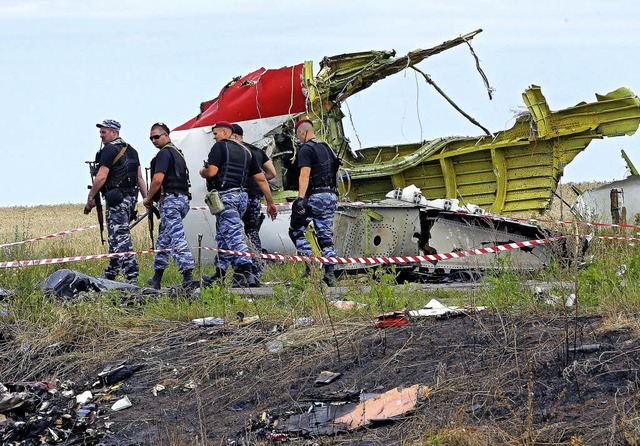 Bewaffnete Separatisten vor einem Trmmerteil der abgestrzten Boeing 777  | Foto: dpa