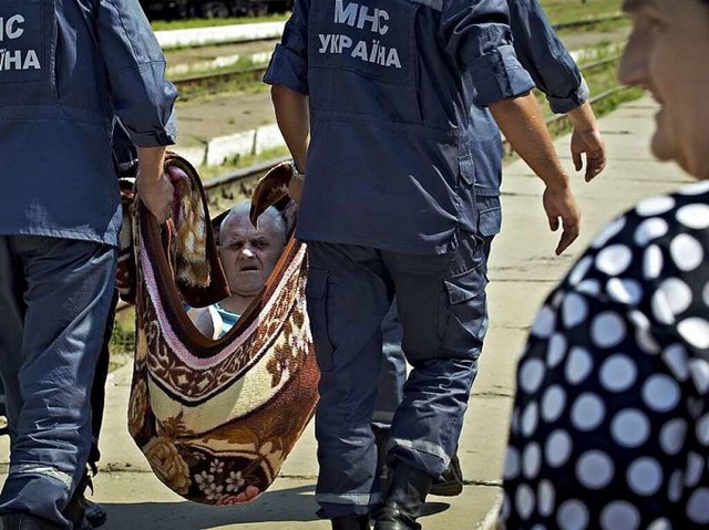 Ukrainische Rettungskrfte tragen in der Nhe von Lugansk  einen Flchtling.  | Foto: dpa