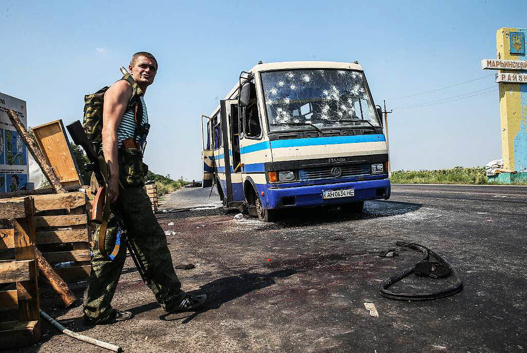 Ein bewaffneter Seperatist steht nahe eines beschdigten Busses der in Donezk attackiert wurde. Zwlf Menschen wurden gettet als der Bus durch pro-russische Seperatisten beschossen wurde.