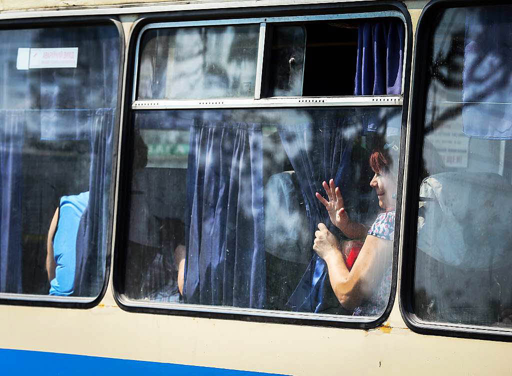 Eine Frau winkt aus dem Bus der gerade den Hauptbusbahnhof in Donezk verlsst.