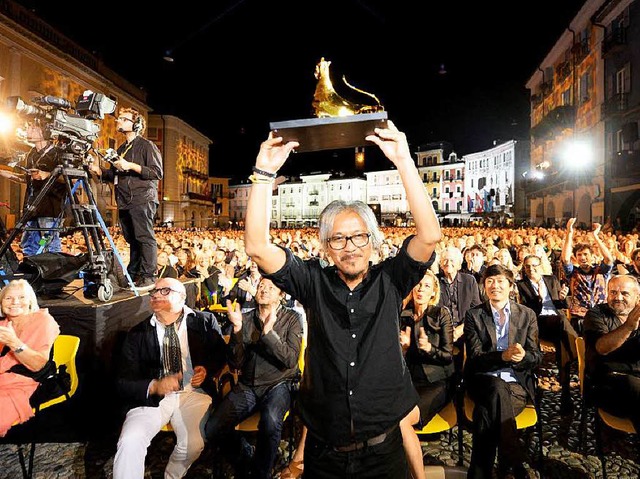 Regisseur Lav Diaz reckt auf der Piazz...Locarno seinen Hauptpreis in die Hhe.  | Foto: dpa