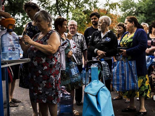 Einwohner warten in der von der ukrain...lagerten Stadt Donezk auf Trinkwasser.  | Foto: AFP