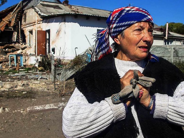 Eine Frau steht vor einem zerstrten Haus nahe Donezk.  | Foto: dpa