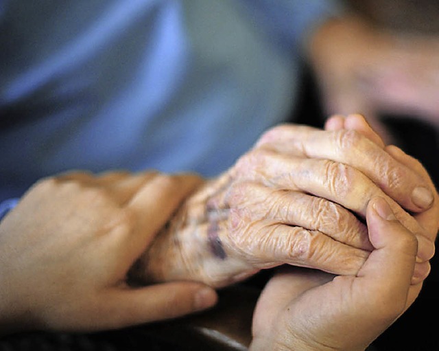 Eine Pflegekraft hlt die Hand einer Bewohnerin.   | Foto: dpa