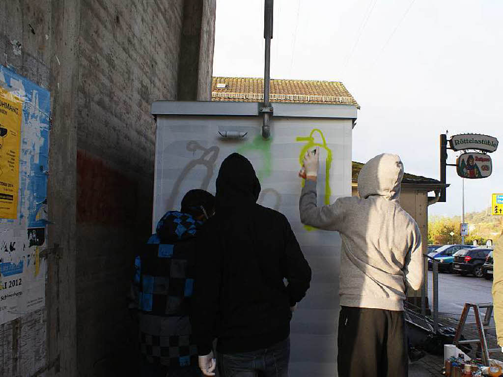 Jungs in Kapuzenpullis sprayen Gasflachen an die Gasstation der Badenova.