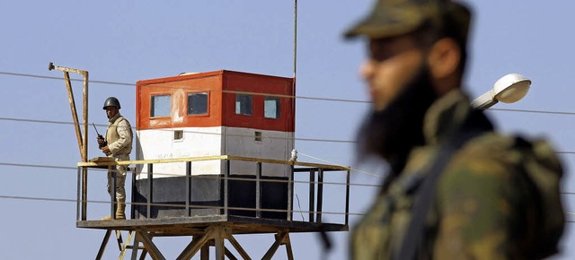 Ein gyptischer Wachmann beobachtet de...fen einen palstinensischen Soldaten.   | Foto: AFP