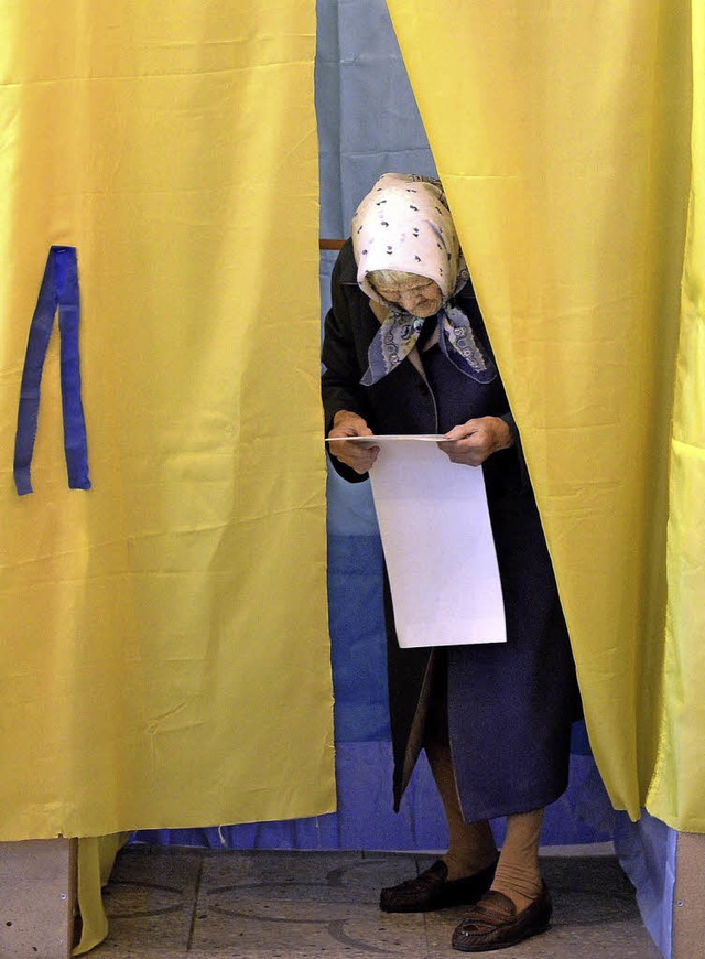 Eine Frau in Lviv (Lemberg) studiert i...ten Wahlkabine den langen Wahlzettel.   | Foto: dpa