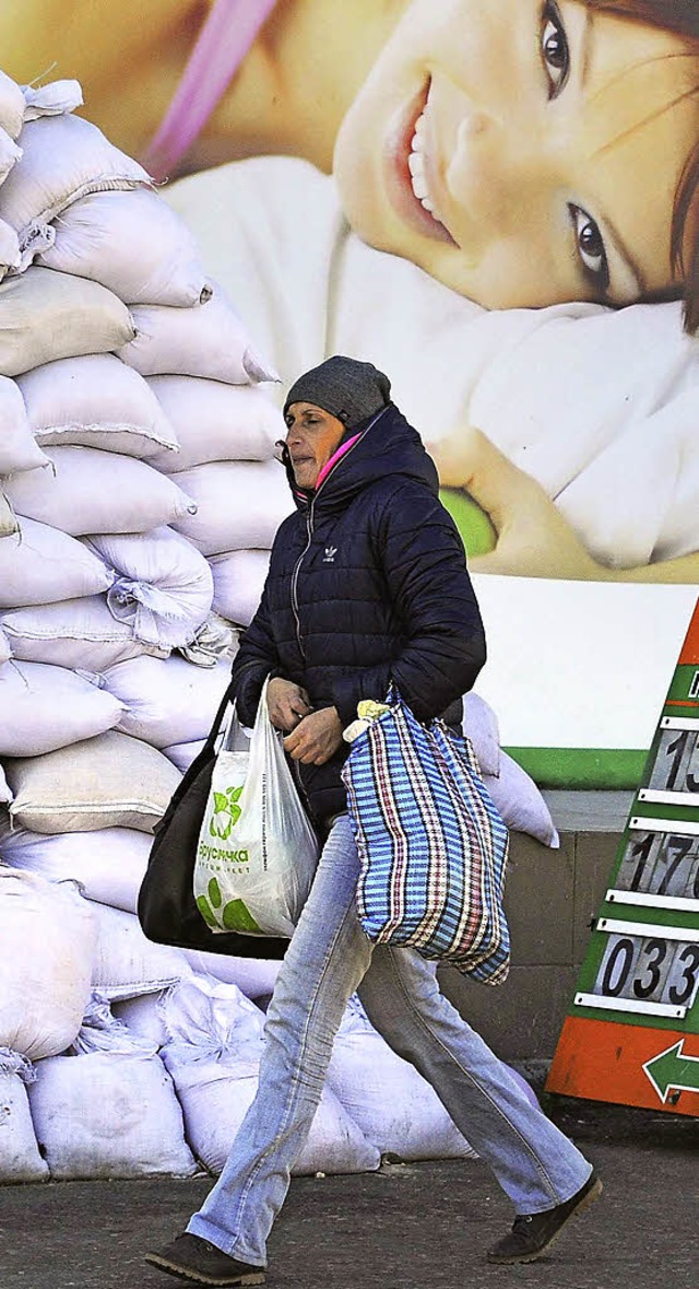 Alltag hinter Sandscken: Eine Frau  geht mit Einkaufstten durch Donezk.  | Foto: AFP