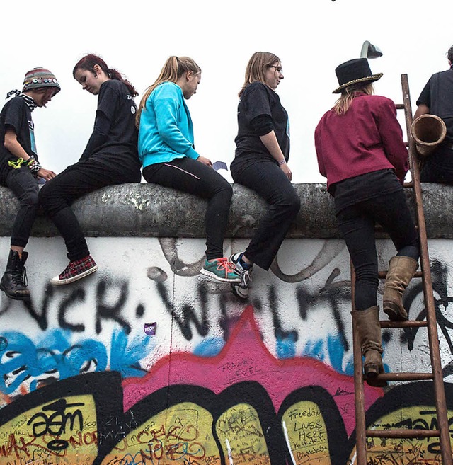 Wie vor 25 Jahren: Junge Leute auf der Mauer an der East Side Gallery.  | Foto: dpa