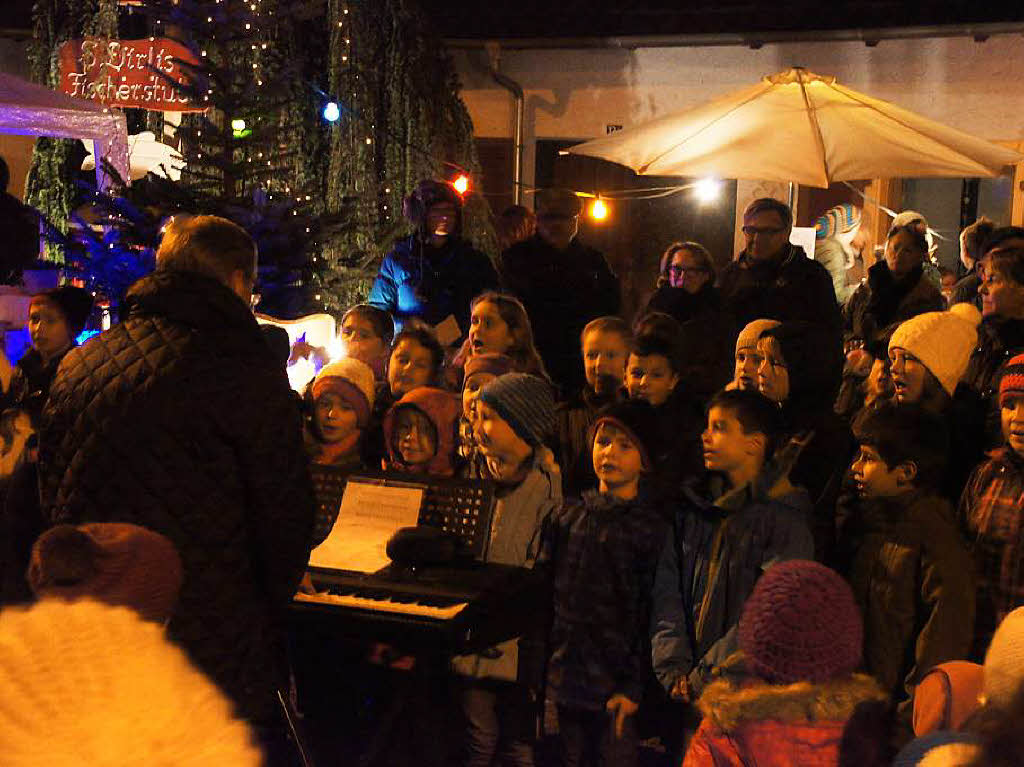 Weihnachtsmarkt in Rheinhausen: Kindergarten und Schulchor sangen mitten auf dem Weihnachtsmarkt, der von Vereinen, Geschftsleuten und Privatpersonen fr einen Abend stimmungsvoll gestaltet war.