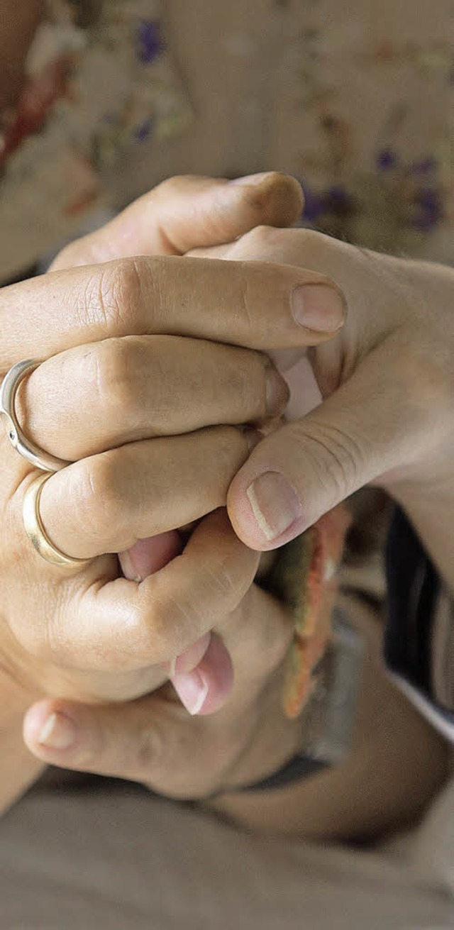 Eine Therapeutin hlt die Hand einer Todkranken.   | Foto: DPA