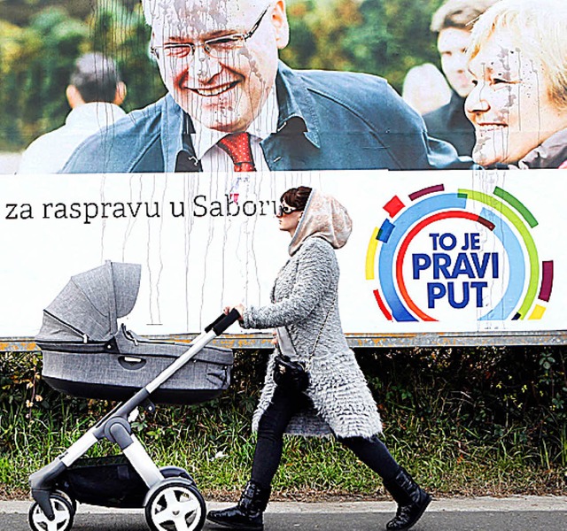 Eine Frau geht an einem Plakat von Prsident Josipovic vorbei.   | Foto: DPA