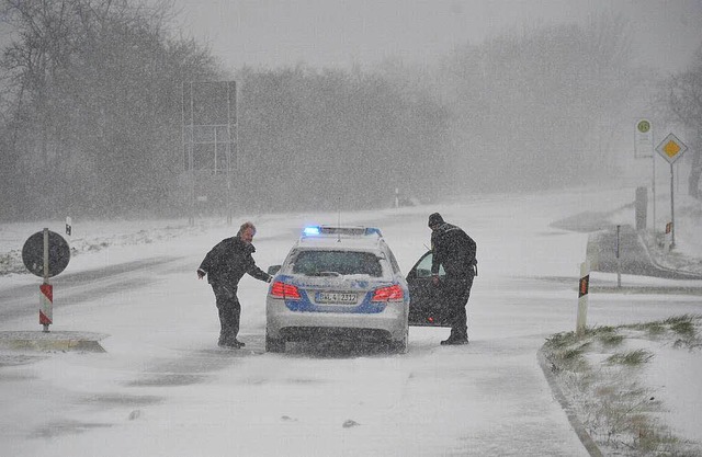 Zwei Polizisten sperren  bei Waldenburg  mit ihrem Auto eine vereiste Strae.  | Foto: dpa