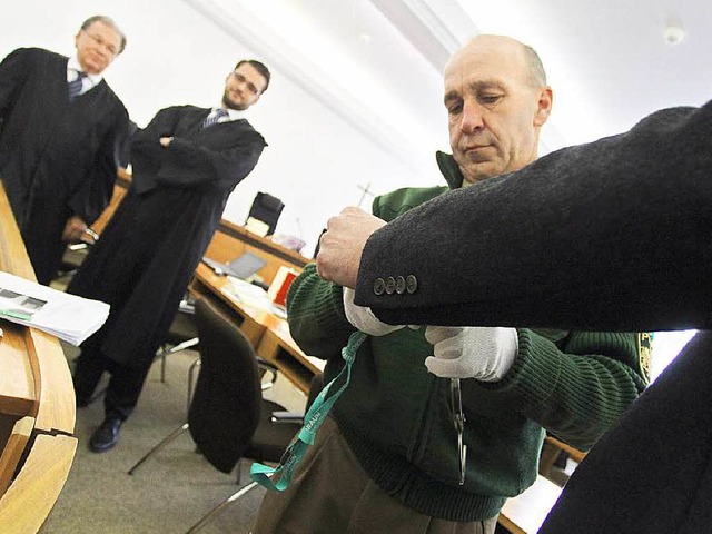 Ein Justizbeamter nimmt dem Angeklagte...n seiner Anwlte die Handschellen ab.   | Foto: dpa