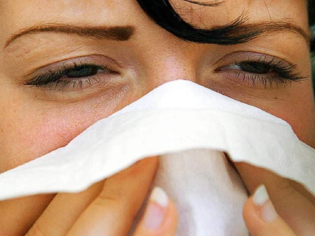 Eine Frau putzt sich mit einem Taschentuch die Nase.   | Foto: dpa