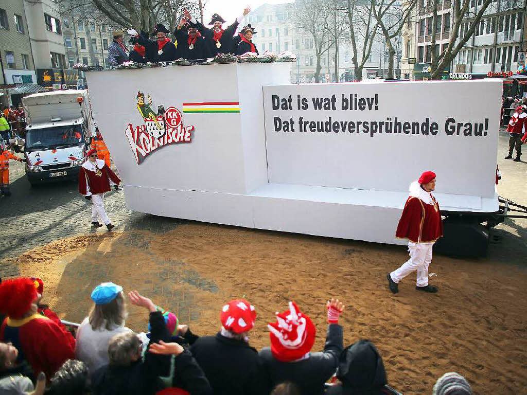 Dieser Motivwagen sollte sich eigentlich mit dem Mordanschlag auf die franzsische Satirezeitschrift Charlie Hebdo beschftigen. Doch das Vorhaben wurde abgesagt – und so zieht der Wagen als Anspielung darauf mit der Botschaft „Das ist, was bleibt! Das freudeversprhende Grau!“ durch die Klner Stadt.