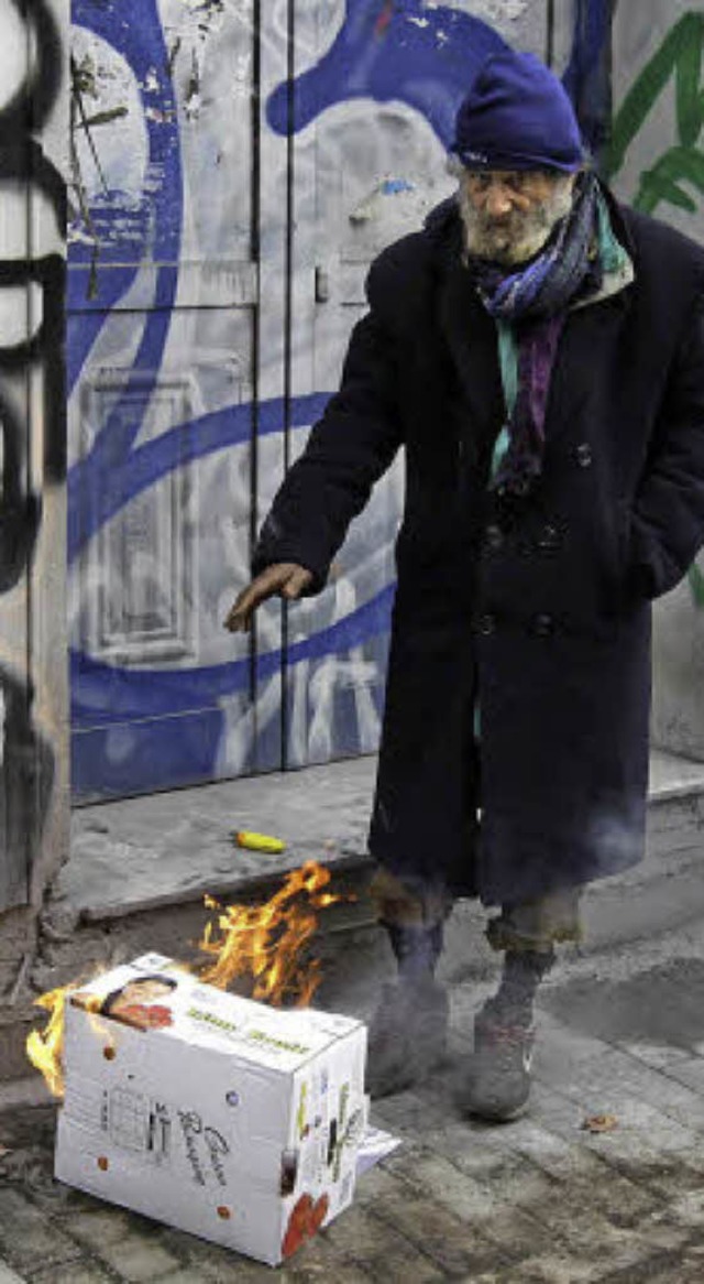 Ein Obdachloser wrmt sich in Athen. L...en nah an oder unter der Armutsgrenze.  | Foto: dpa