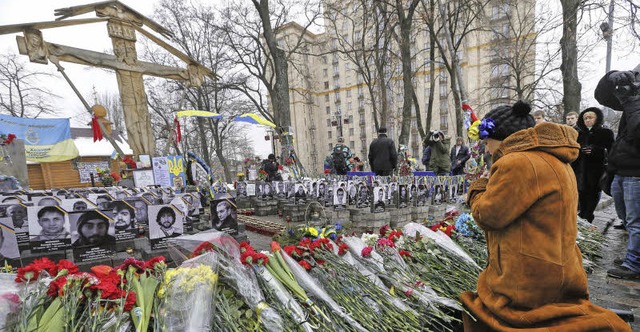 Eine Frau legt auf dem Maidan zu Ehren...inem Jahr Erschossenen Blumen nieder.   | Foto: dpa