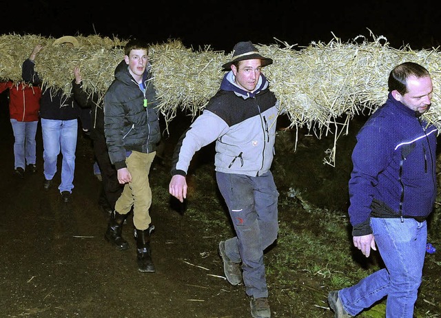 Das strohumwickelte Holzkreuz wird zum Berg getragen.   | Foto: (2)  knstle