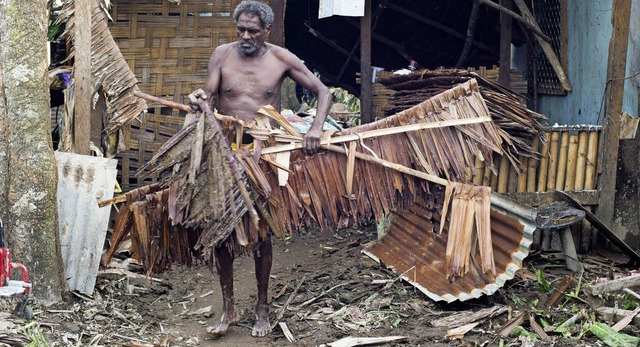 Ein Mann versucht, seine vom Sturm schwer beschdigte Behausung aufzurumen.   | Foto: dpa