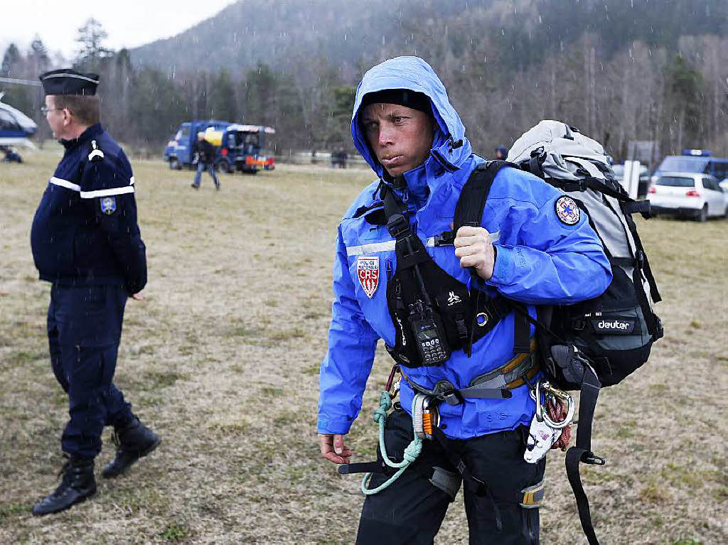 Ein Helfer luft in Seyne les Alpes zu einem Helikopter, der ihn zu dem Absturzort bringen soll