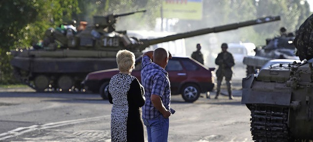 Ein Paar  beobachtet, wie  Panzer der ...ie Waffen schweigen bis heute  nicht.   | Foto: AFP