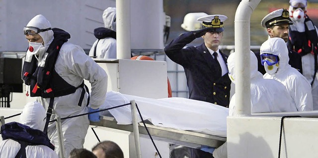 Mitglieder der italienischen Kstenwache bringen  geborgene Leichen von Bord.  | Foto: dpa