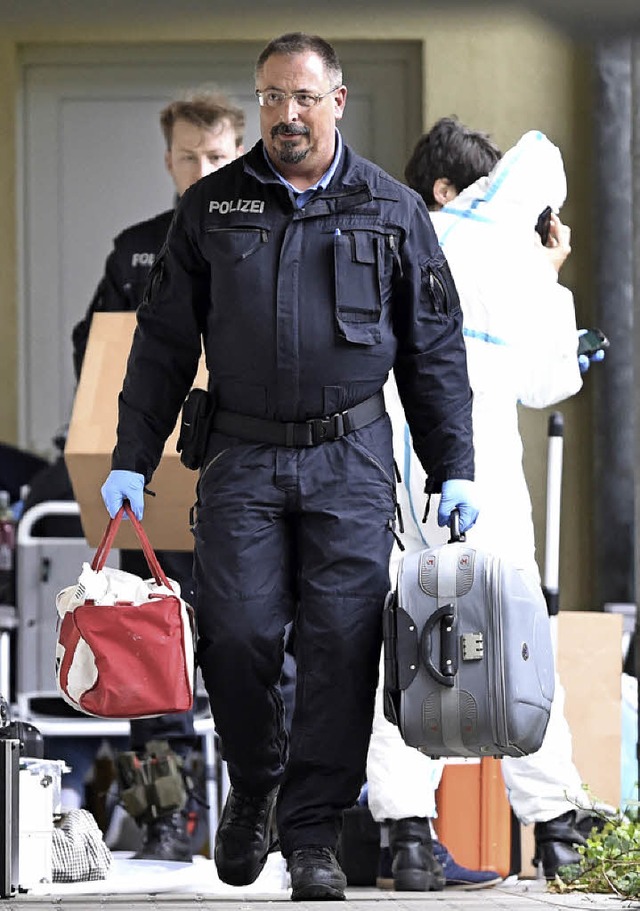 Polizisten tragen Gegenstnde aus der Wohnung der Verdchtigen in Oberursel.  | Foto: DPA