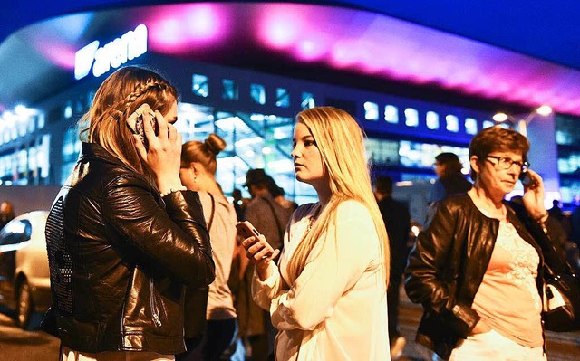 Zuschauer stehen telefonierend vor der Halle.  | Foto: dpa