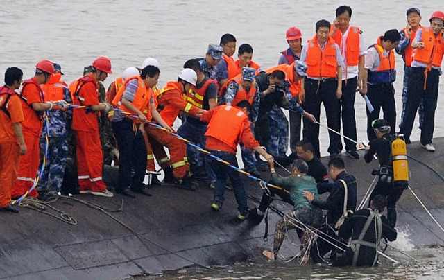 Rettungskrfte ziehen eine ltere Frau aus dem Wasser.   | Foto: AFP