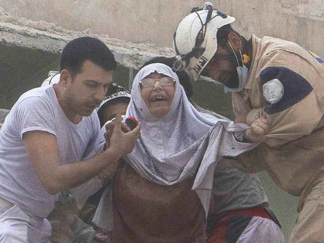 Nach einem Angriff mit Fassbomben in A...en  Helfer diese Frau in Sicherheit.    | Foto: AFP