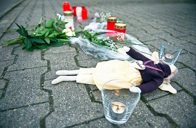 Kerzen, Blumen und eine Puppe liegen i...slingen) vor dem Wohnhaus der Familie.  | Foto: dpa