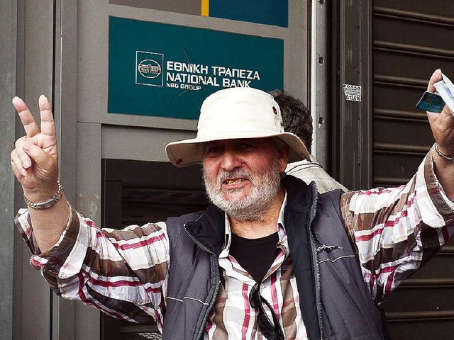 Ein Grieche freut sich, dass der Automat noch etwas Geld ausgespuckt hat.   | Foto: AFP