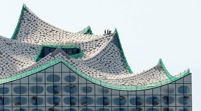 Fast nur mit der Lupe erkennbar: Bauarbeiter auf dem Dach   | Foto: dpa
