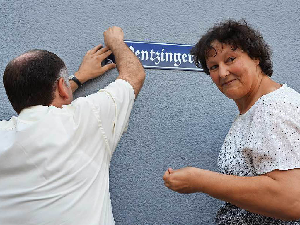 Thomas Breig und Claudia Dischinger montieren das neue Schild an die Wand des Alten Rathauses.