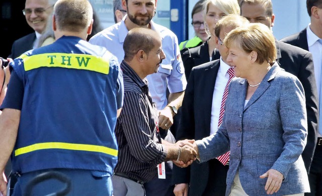 Angela Merkel begrt in der Flchtlingsunterkunft von Heidenau einen Helfer.   | Foto: dpa