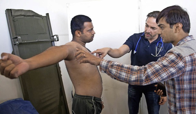 Ein Arzt untersucht einen Flchtling in einer Unterkunft in Stuttgart.   | Foto: DPA