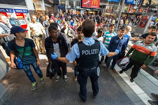 Ein Polizist weist den Flchtlingen am...hnhof den Weg zur Registrierungshalle.  | Foto: dpa